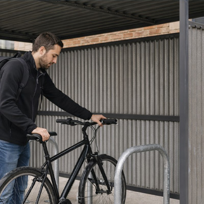 Man putting his bike in a Black Traditional Cycle Shelter